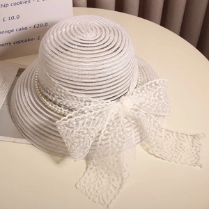 Vue détaillée d'un chapeau de paille blanc élégant avec un grand nœud en dentelle.