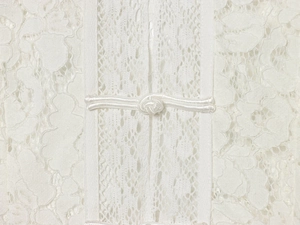 Close-up of white lace fabric texture and traditional handmade frog button detail