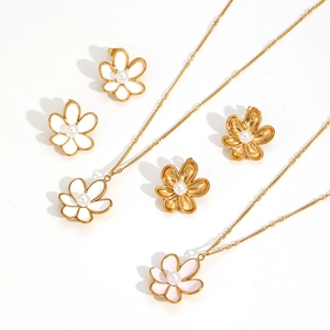 Floral stainless steel jewelry set with gold enamel flowers and pearls on white backdrop