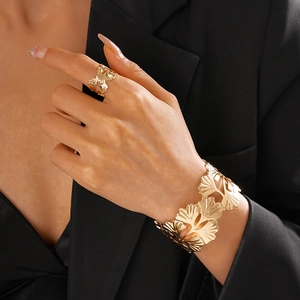 Détail du lot de bracelet manchette et bague dorés avec motif de feuilles de ginkgo ajourées