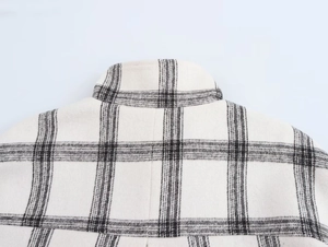 Detailed macro shot of the black and white plaid wool-feel jacket collar and shoulder