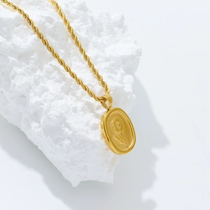 Detail of 18k gold plated titanium necklace with sunflower pendant on white rock