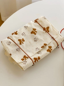 Close-up of cute bear pattern on a cream fabric makeup bag with orange polka dots
