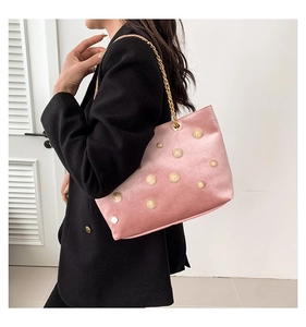 Pink velvet tote bag with gold sun metal charms and chain strap on a black blazer