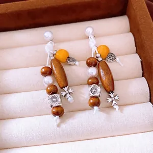 Bohemian wood bead earrings with silver flower, cross, and pearl charms in a gift box