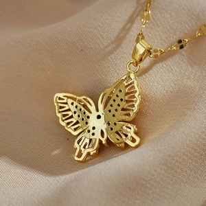 Detail of a golden butterfly pendant with intricate hollow design and polished finish