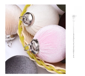 Close-up of pink and white velvet Christmas balls in a woven basket with metal caps