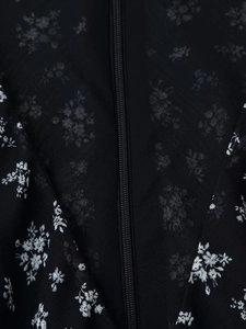 Detailaufnahme von verdecktem Reißverschluss und floralem Chiffonstoff am schwarzen Kleid