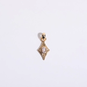 Macro detail of gold-plated rhombus pendant with zircon center and sunburst texture