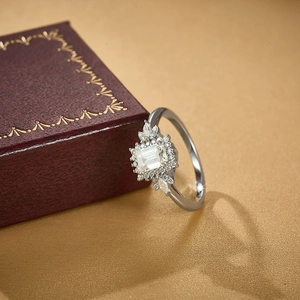 925 sterling silver ring with emerald cut moissanite in flower halo design on gold surface