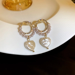 Detailed macro view of gold-tone circle earrings with rhinestones and heart pearl charms