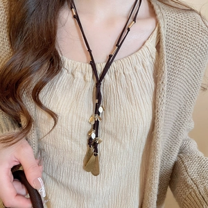 Detail of vintage necklace with brown leather cord and multiple gold leaf pendants
