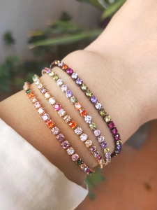Detail of four colorful zircon tennis bracelets in rose gold, gold, silver, and black finish