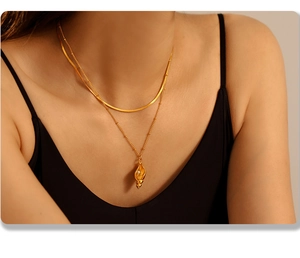 Details einer geschichteten Goldkette mit Muschel-Anhänger und eleganter Schlangenkette