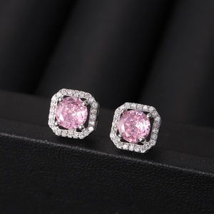 Macro shot of pink zircon earrings featuring a round center stone and a halo of white gems