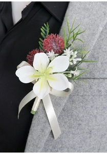 Detail of white artificial lily boutonniere with red floral accents on grey suit lapel