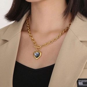 Détail du collier à chaîne dorée avec cristal gris foncé en cœur et fermoir OT