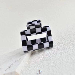 Macro shot of square black and white checkered hair claw clip in polished acetate