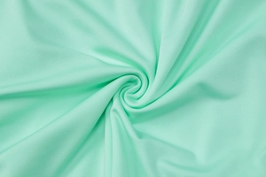 Close-up of mint green ruched knitted fabric texture with soft drape and glossy finish
