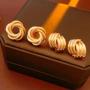 Macro view of gold geometric intertwined knot earrings on a dark brown gift box