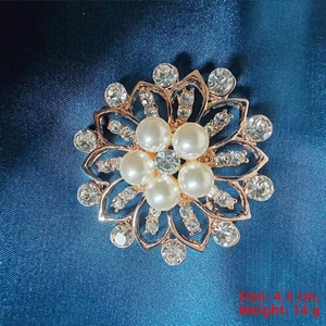 Detail of rose gold camellia brooch with white pearls and sparkling rhinestones