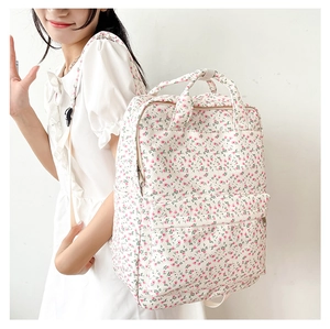 Detailed side view of white floral backpack with pink blossoms on a female model