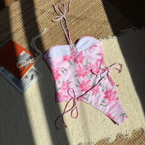 Flat lay of pink lily print bikini with adjustable ties and golden bead details