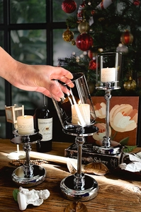 Three-piece silver metal candle holder set with glass shades and white pillar candles