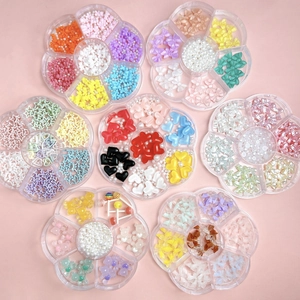 Flat lay of 8 petal-shaped cases filled with colorful resin bows and pearls for nail art