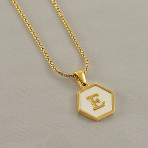 Detailed close-up of 18k gold-plated hexagon pendant with white shell and letter E inlay