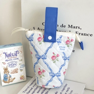 Gedetailleerde close-up van een gewatteerde bloemen etui met strikpatronen en blauw handvat