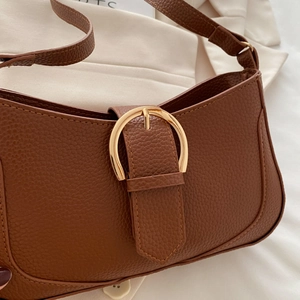 Close-up of litchi texture brown leather underarm bag with gold metal D-buckle detail