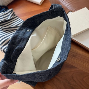 Detailed interior of blue denim tote bag with cream canvas lining and magnetic clasp