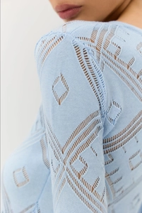 Dettaglio dell'abito in maglia azzurro con raffinati motivi geometrici traforati