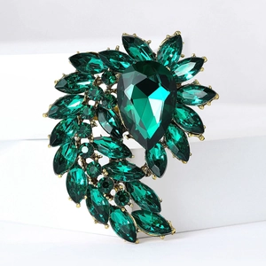 Detail view of a vintage gold alloy brooch with emerald green pear-shaped rhinestones