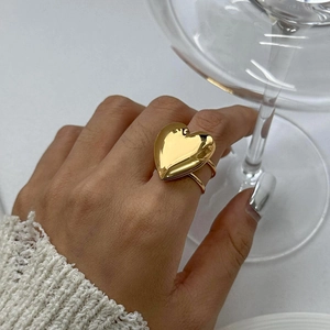 Close-up of a gold heart-shaped stainless steel ring worn on a model's hand