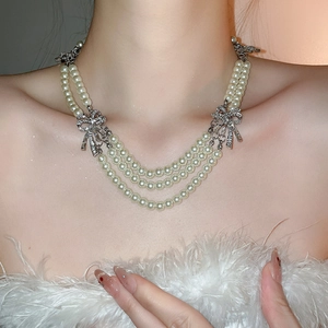 Close-up of elegant double-layer pearl necklace with sparkling rhinestone bow accents