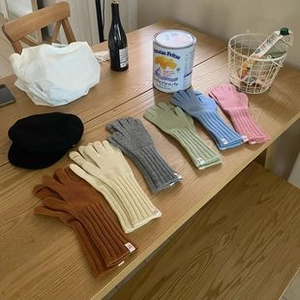 Vista plana de guantes de lana de punto coloridos y una boina negra en mesa de madera