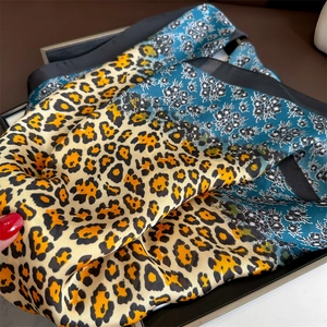 Detail of silk scarf with leopard print and blue floral patterns on dark background