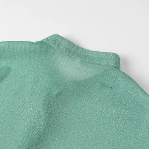 Détail du col de chemise vert menthe avec un tissu brillant à la texture métallique