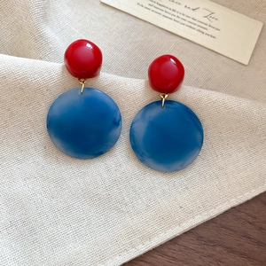 Close-up of retro red and blue acrylic resin drop earrings on a soft linen background