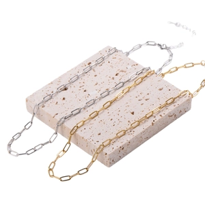 Gold and silver stainless steel paperclip necklaces on a minimalist travertine stone