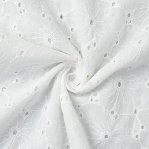 Macro shot of white cotton eyelet embroidery fabric with delicate floral lace patterns