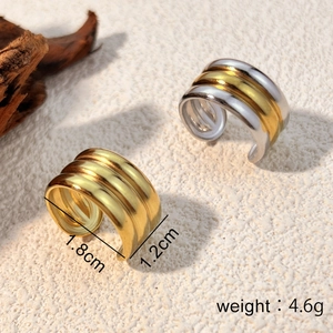 Orecchini ear cuff ampi con finiture dorate e bicolore su uno sfondo materico elegante