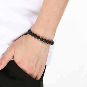 Macro shot of matte black onyx beads bracelet with lava stone on a man's wrist