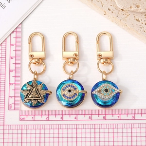 Golden Evil Eye keychains with blue crystals and rhinestones on a white background
