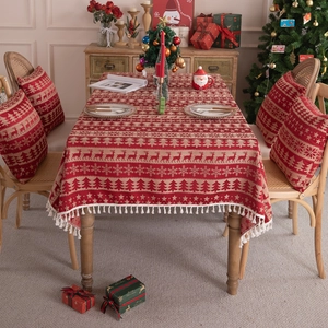 Red Christmas tablecloth with reindeer and snowflake patterns featuring white tassels