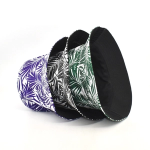 Detailed view of reversible tropical palm print bucket hats in purple, black, and green colors