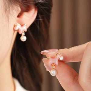 Detailed view of pink puppy earring with pearl accent and 18K gold plating on ear