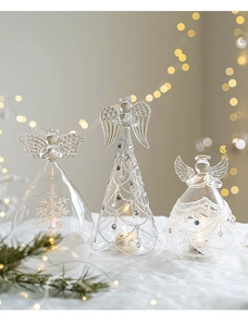 Close-up of three glass angel ornaments with frosty snowflake patterns on white fabric